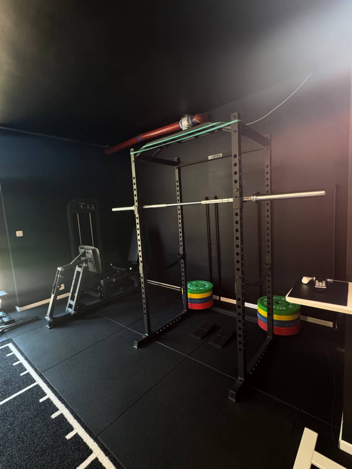La cage à squat du centre KINE+, disques de couleur posés au pied et presse horizontale sur la gauche