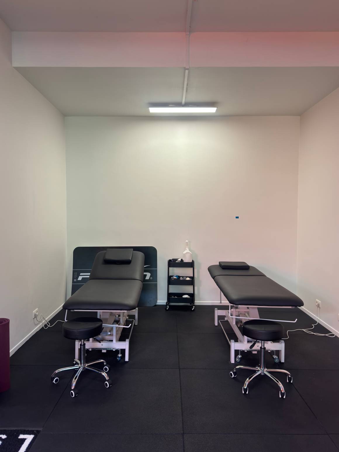 Deux tables de soin du centre KINE+, chacune avec son tabouret, dans une pièce claire