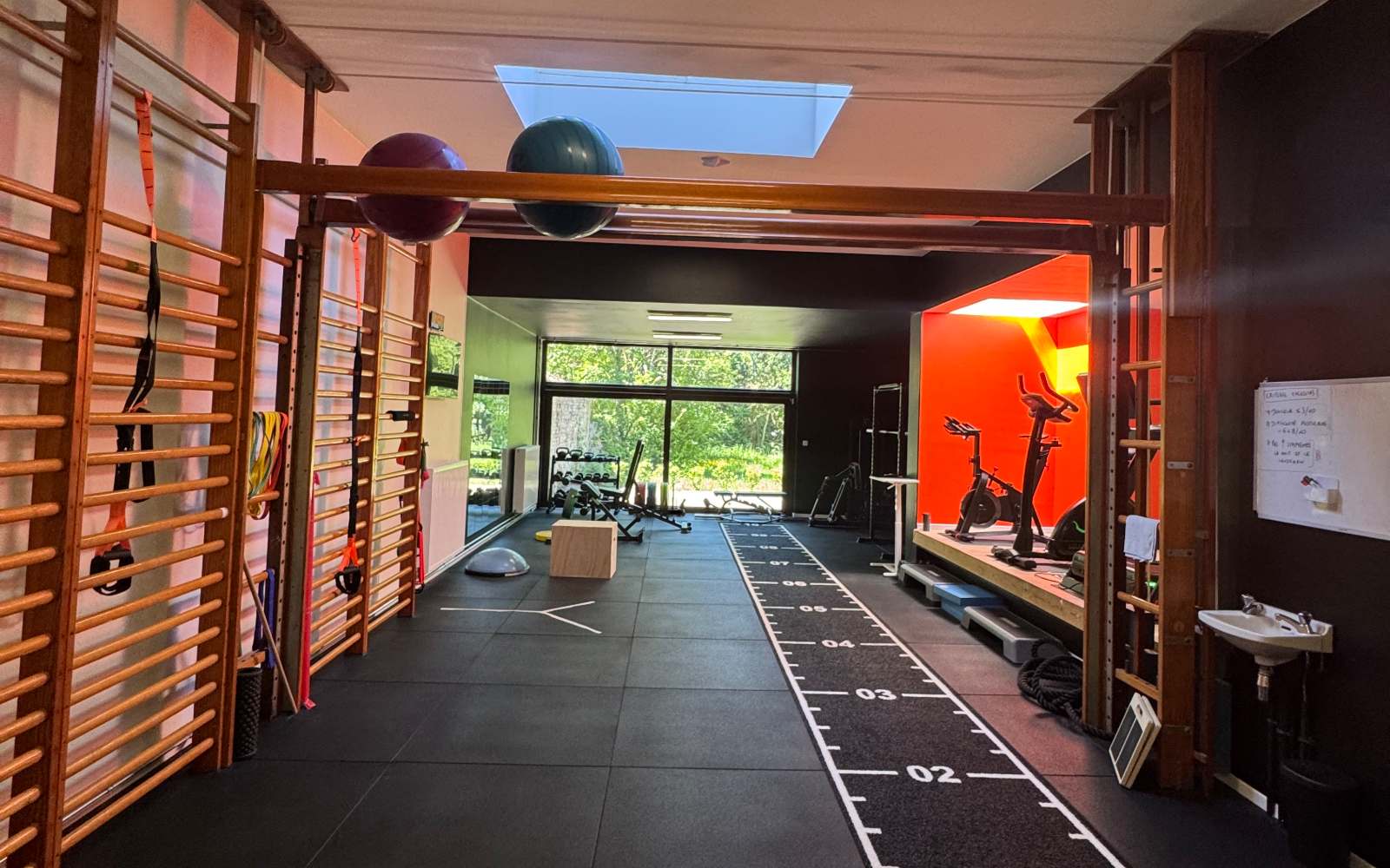 Le centre KINE+ à Ans en enfilade : espaliers, piste graduée au sol et zone cardio au fond