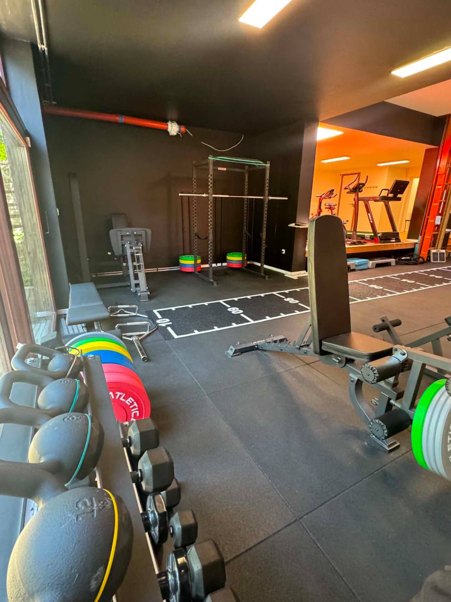 Le plateau de rééducation du centre KINE+ : kettlebells, haltères et disques au premier plan, cage à squat au fond